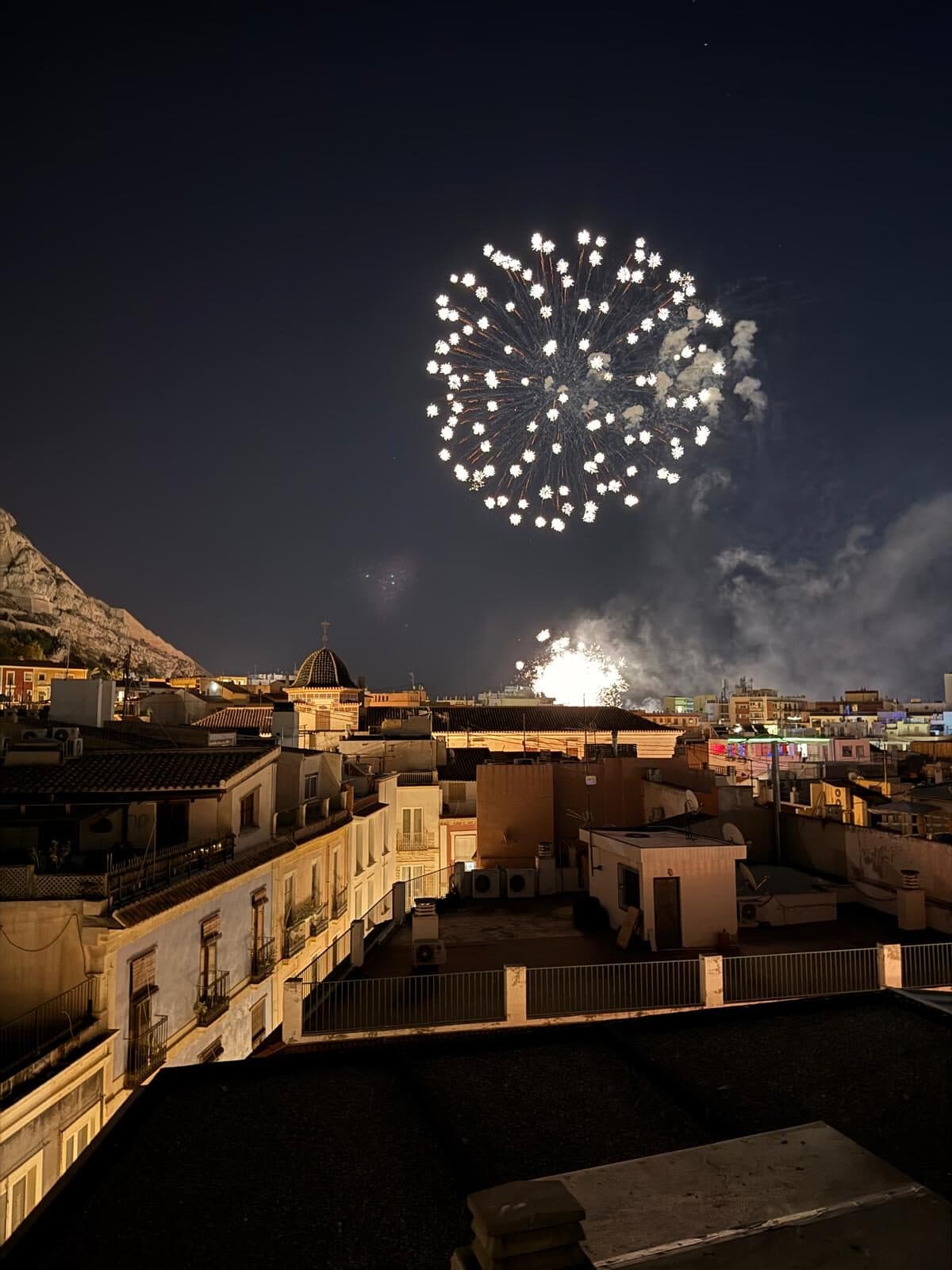 Fireworks bursting over the Alicante rooftops at night
