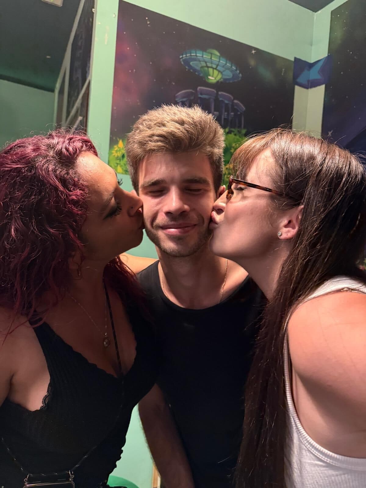 Three members laughing together, cheek kisses
